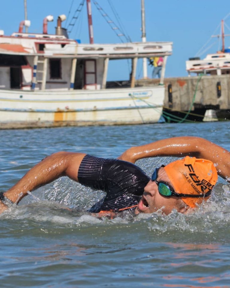 Nadador en una travesía de aguas abiertas junto a un puerto pesquero
